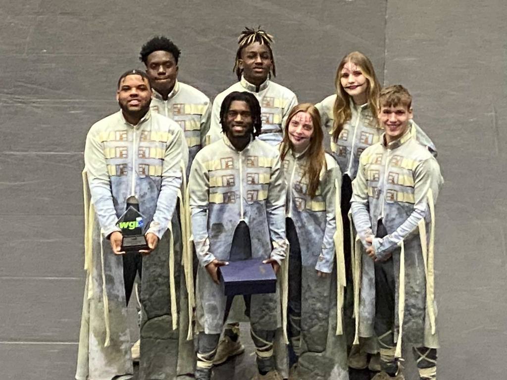 A group of seven percussionists smiling with their award after their performance