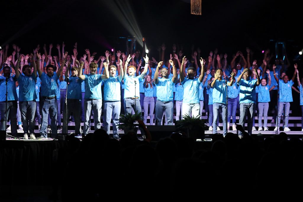 A group of students singing and raising their hands