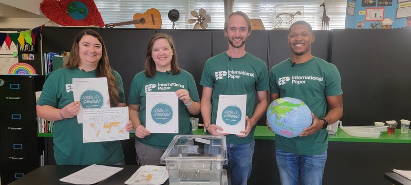 4 Environmental, Electrical and Mechanical Engineers pose with packets of learning material